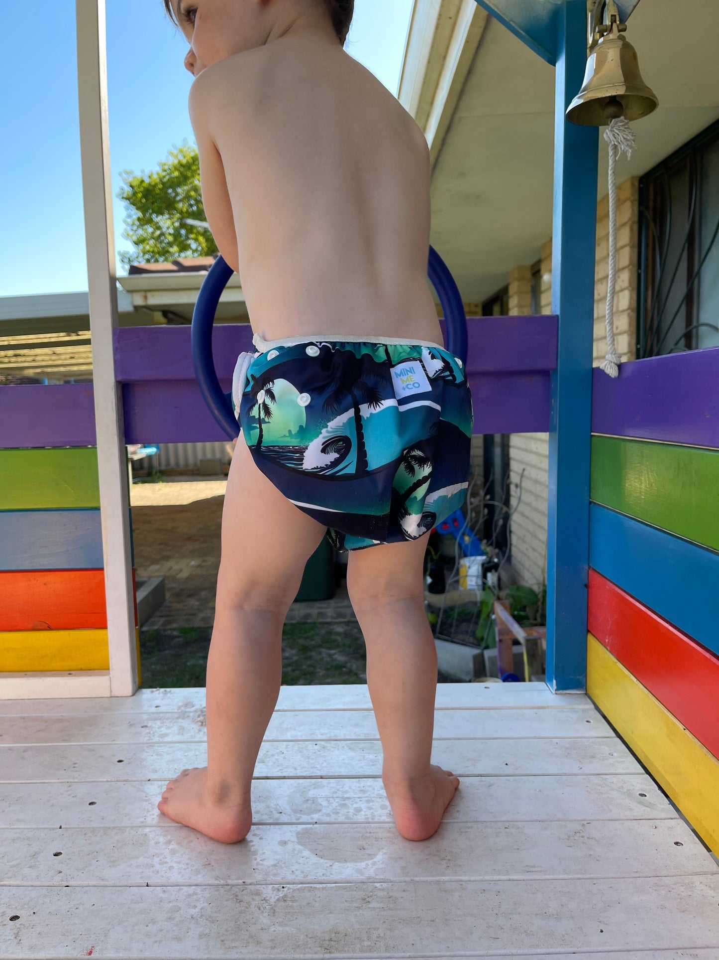 Reusable swim nappy in tropical palm tree design by Mini Me & Co, offering soft lining and adjustable snaps for growing babies and toddlers.